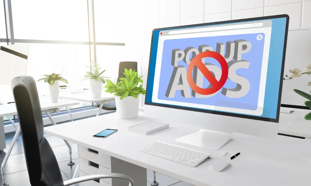 W biurze stoi uruchomiony monitor, na którym wyświetla się duży komunikat o zablokowaniu reklam typu pop-up. Oznacza to, że zainstalowany jest Adblock.